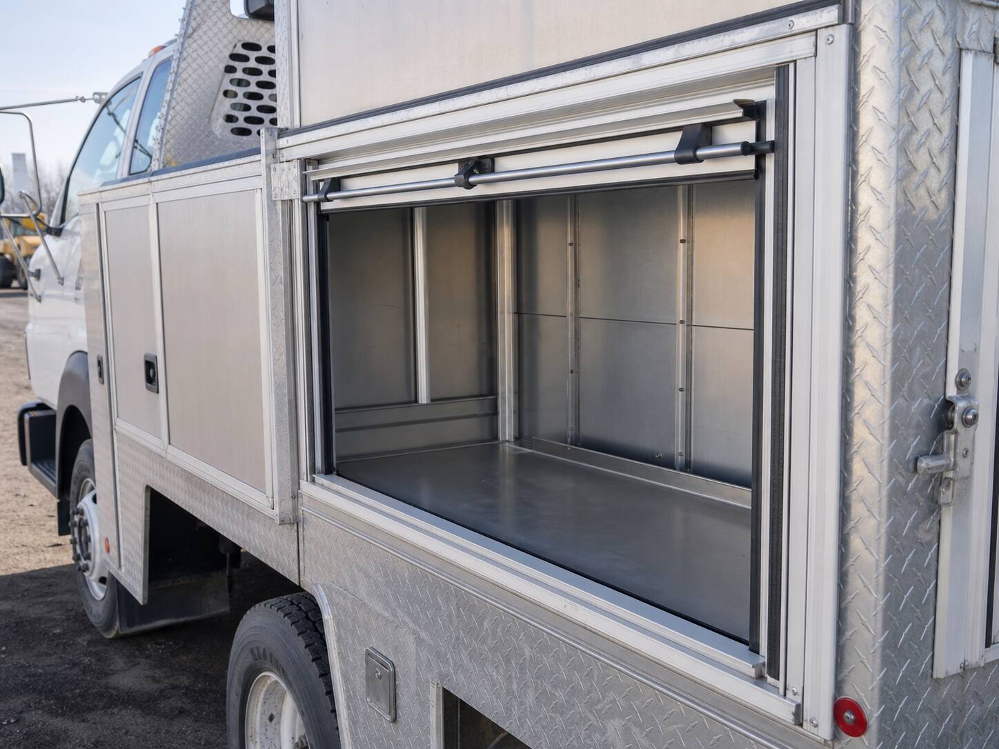 Open service-truck body compartment framed with extruded aluminum and diamond-plate panels
