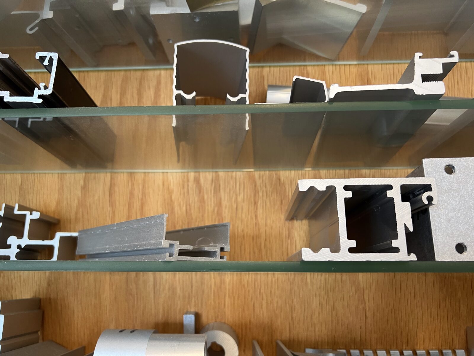 Three aluminum extrusion samples side by side — mill finish, anodized, and powder-coated